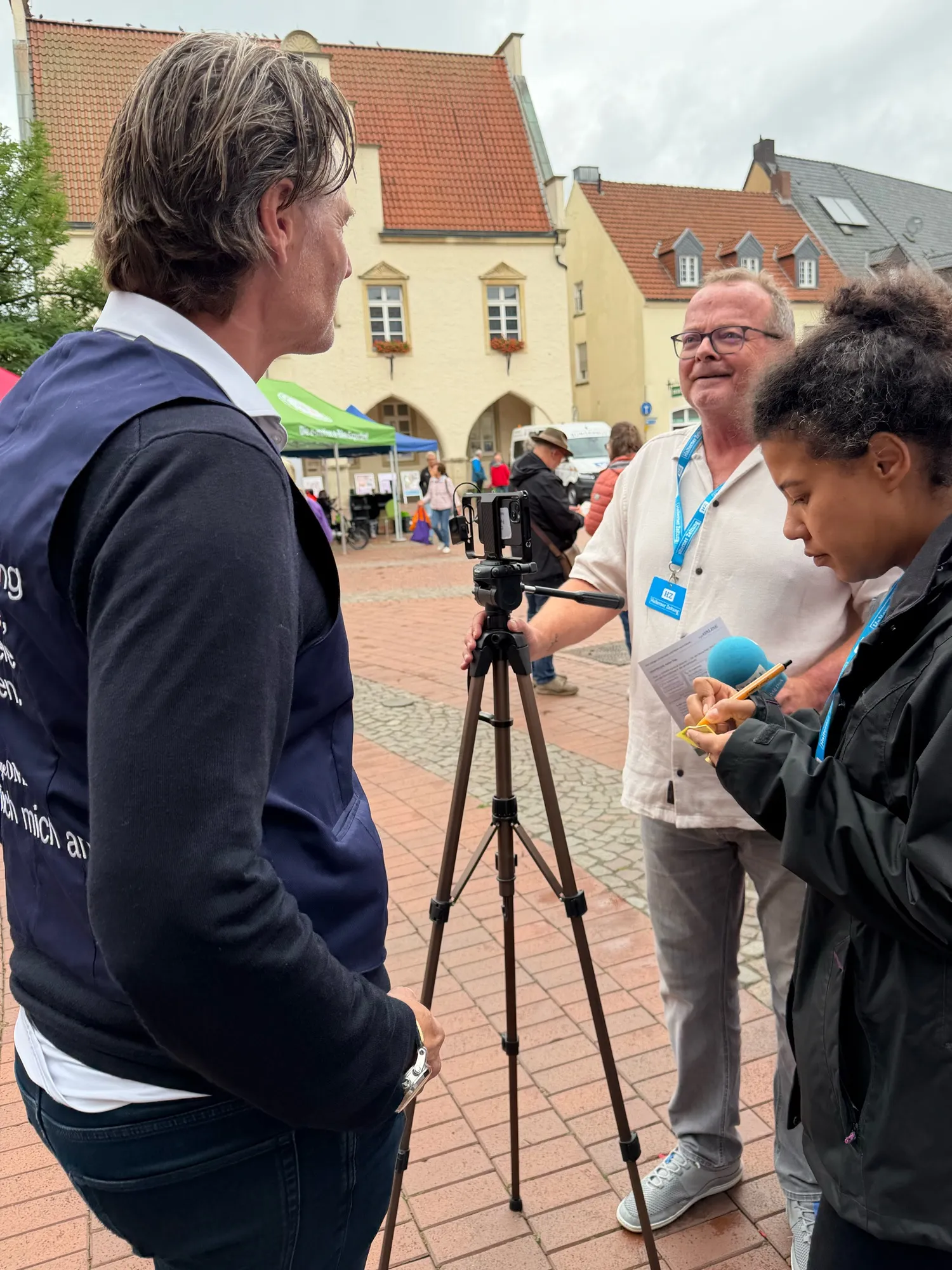 Interview auf dem Marktplatz: Eine Reporterin macht sich Notizen, ein Kollege steht an der Kamera