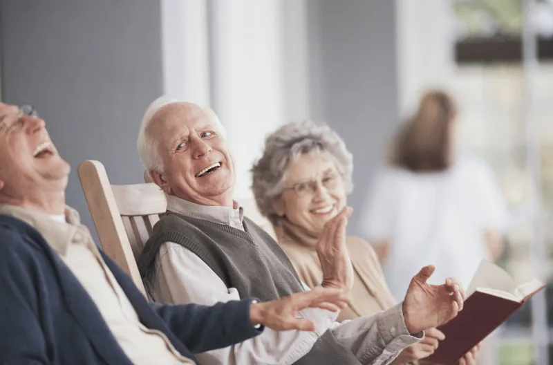 Ältere Menschen sitzen auf einer Veranda und lachen gemeinsam