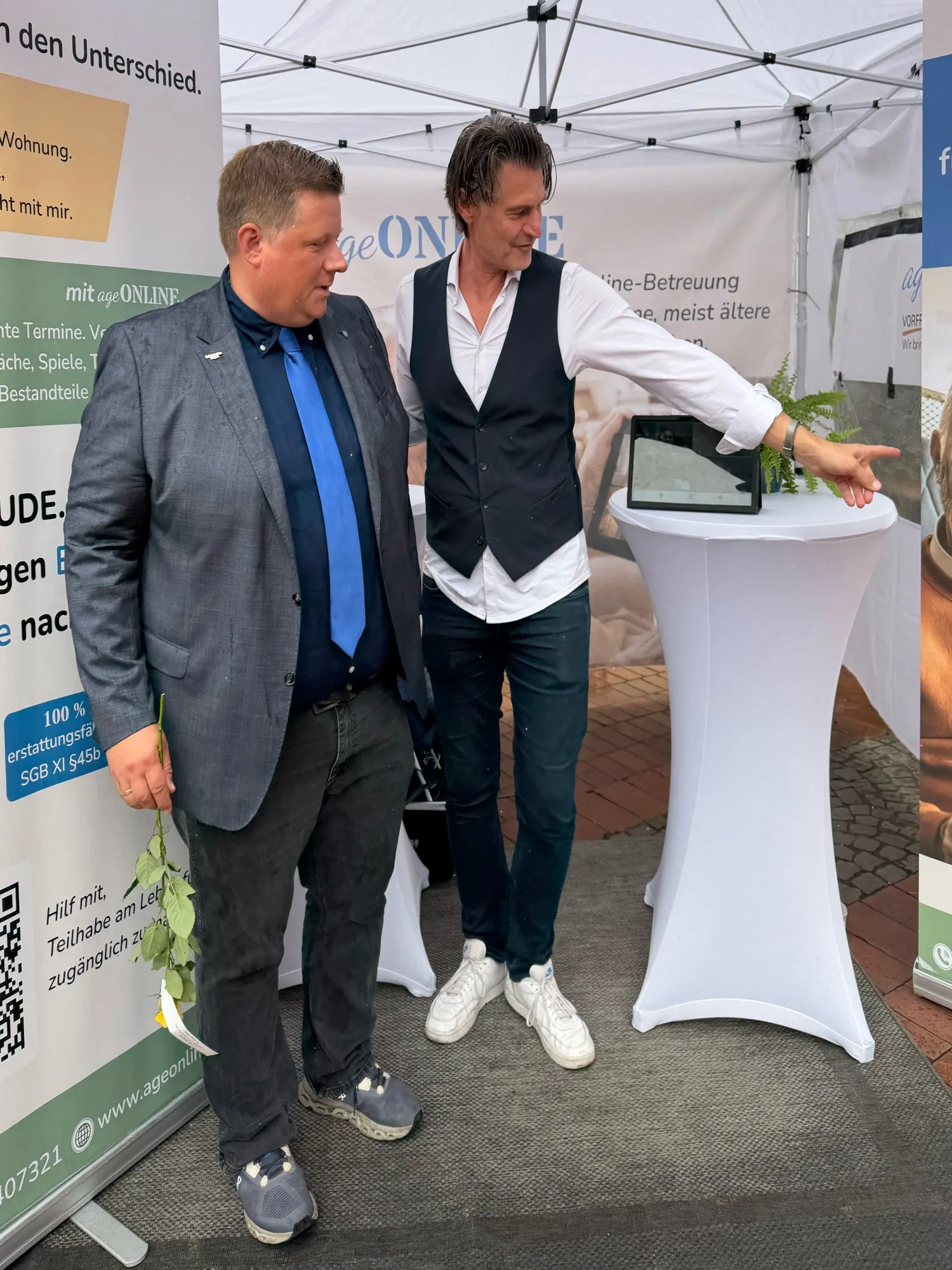 Am ageONLINE-Stand: Bürgermeister Andreas Stegemann im Sakko lässt sich etwas auf einem Tablet zeigen