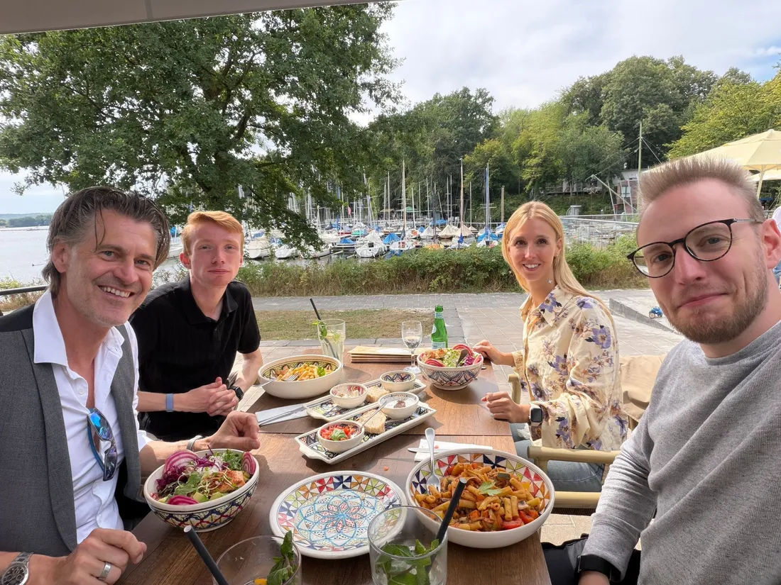 Das Team beim gemeinsamen Mittagessen auf einer Terrasse am See